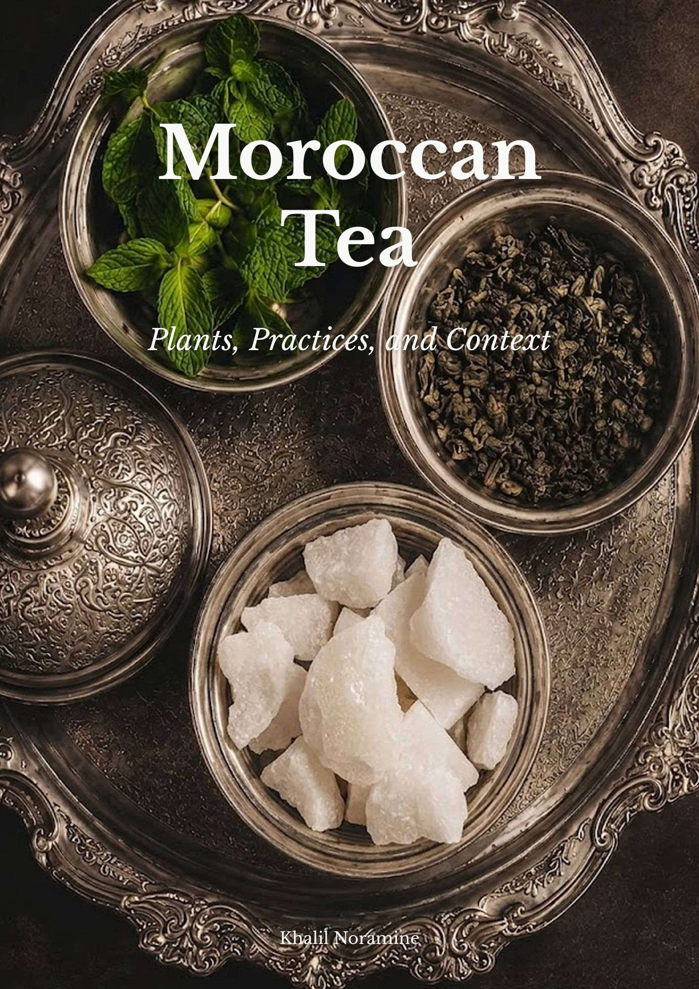 Ornate Moroccan silver tray with fresh mint, green tea leaves, and traditional sugar pieces for preparing Moroccan tea.
