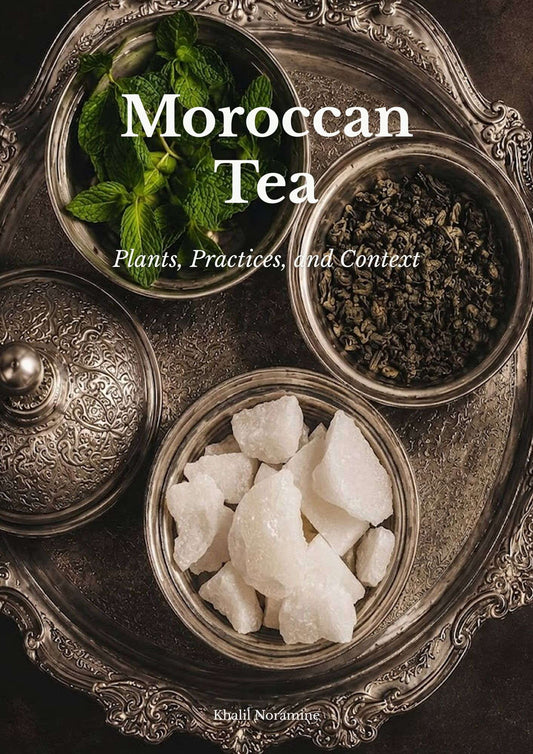 Ornate Moroccan silver tray with fresh mint, green tea leaves, and traditional sugar pieces for preparing Moroccan tea.